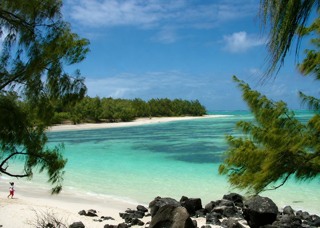Plage Île aux Cerfs à l’île Maurice, bordée de sable blanc et de rochers volcaniques, avec un lagon turquoise cristallin et une végétation tropicale luxuriante